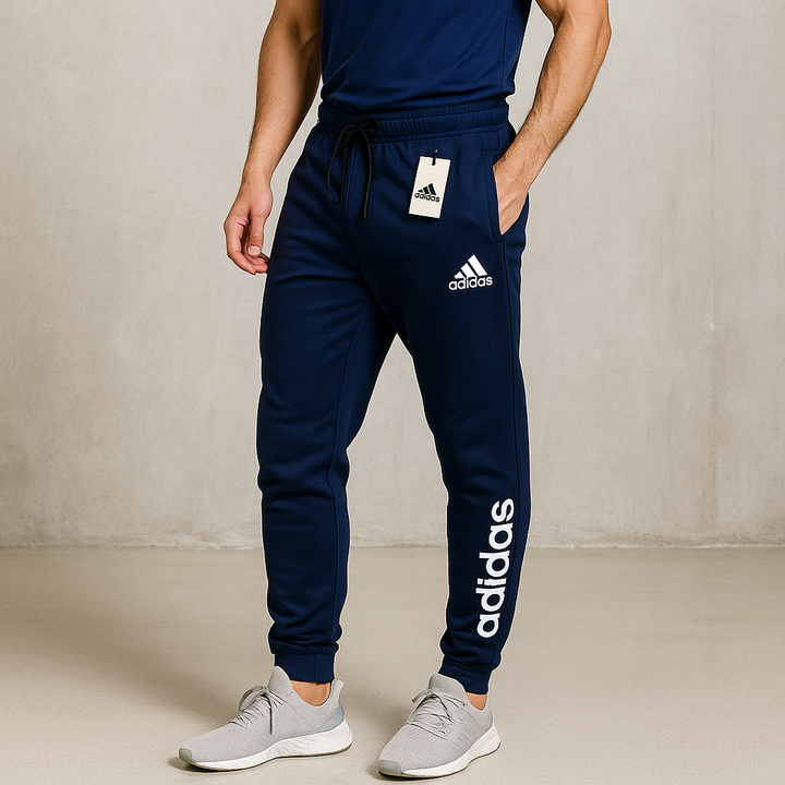 Person wearing navy Adidas tracksuit with a plain background